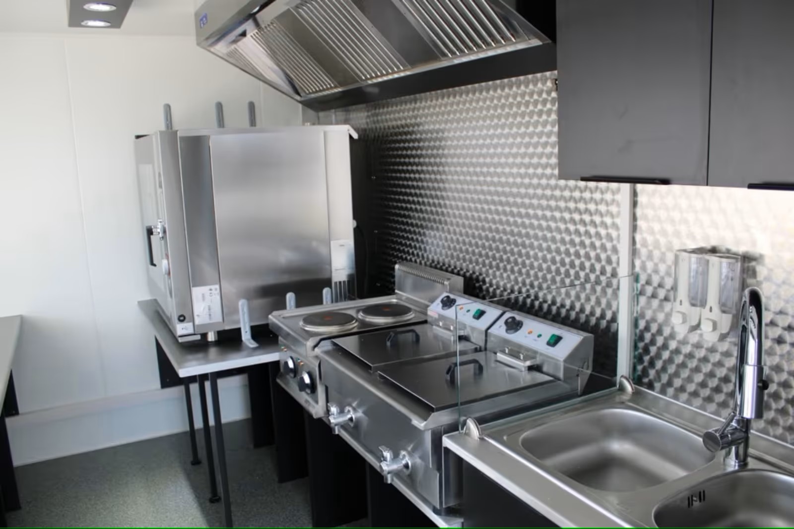 Imbissanhänger Edelstahl Verkaufstheke links rechts hinten schwarze Möbel